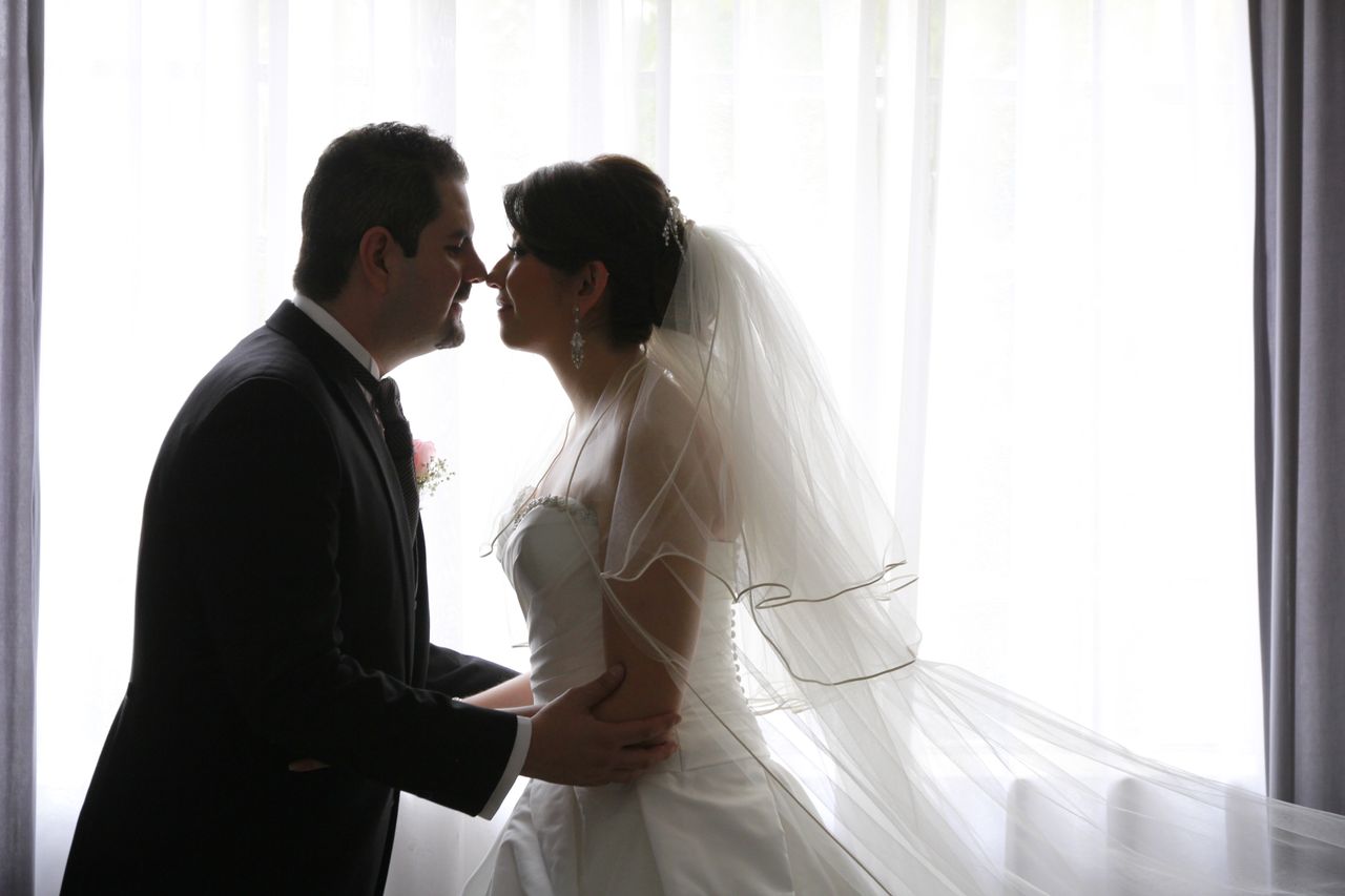 A bride and groom sharing an intimate moment by the window, showcasing love and elegance.